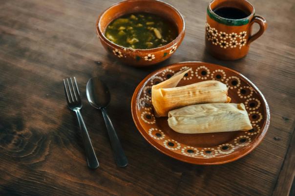 Plate with two tamales on a wooden table.