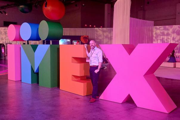 Image of worker stood next to a large sign spelling IMEX