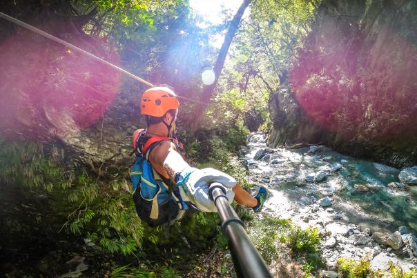 Person ziplining through a forest, over a river
