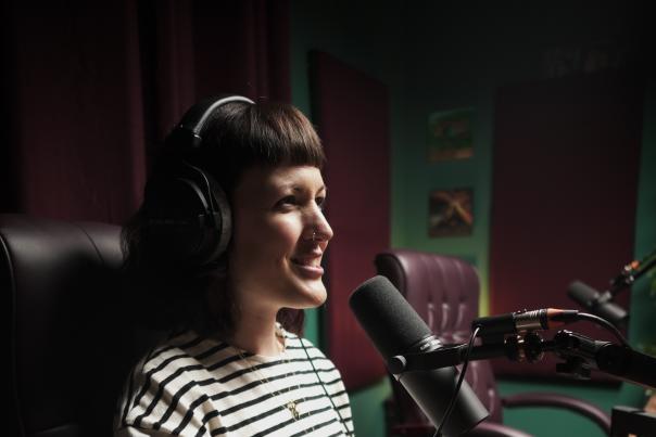 Jenn Clempner talking in a recording booth over a microphone