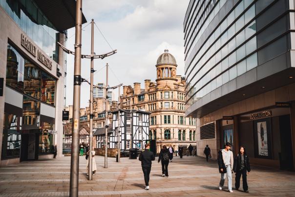 People walking along street in Manchester with architecture in the background