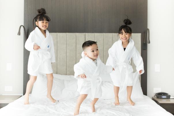 Three kids jumping on a bed at Hotel X in Toronto