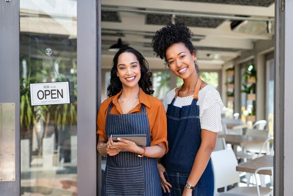 Two successful woman waitress standing at cafe entrance door