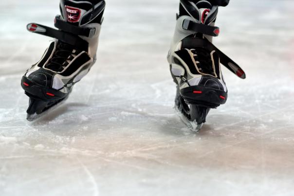 A detail photo of an ice skater's skates on an ice rink
