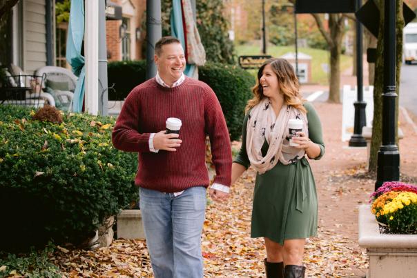 A couple walking hand in hand with coffee cups through the leaf covered, bricked lined streets of Historic Dublin in the fall.