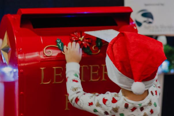 Child putting letting in mailbox for Santa