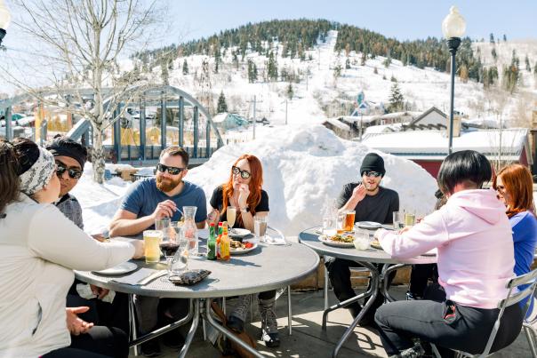 Group of friends eating at bridge on the patio on a spring day apres ski