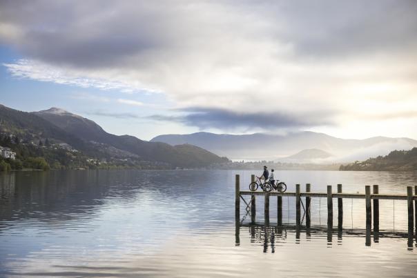 Two people at a pier with bikes overlooking a lake