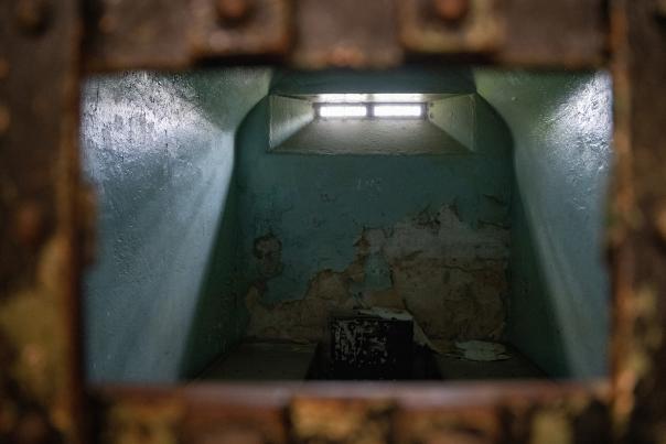 An old, eerie jail cell with a glowing window at the top