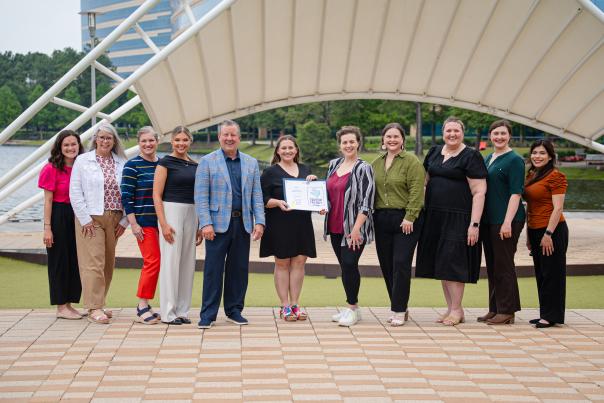 Visit The Woodlands accepts the Tourism Friendly Certification for The Woodlands Township. From left: Andrea Day, Julie Quinn, Ashley Fenner, Brooklyn Newell, Nick Wolda, Amber Parsley, a representative from the Governor's Office, Elizabeth Eddins, Vargo Williams, Rachael Varner, and Carla Twidell.