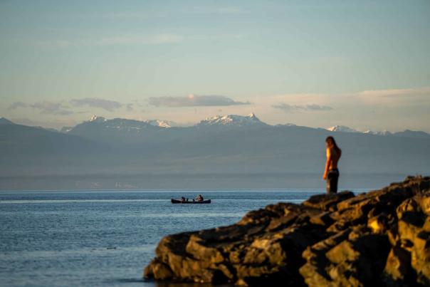 A person looking over the ocean on a rocky cliff.