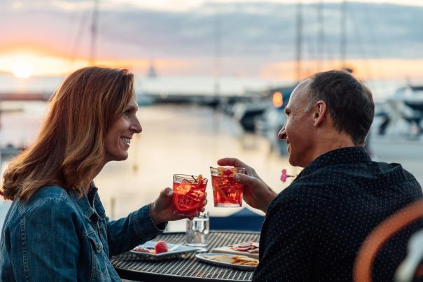 Couple drinking Old Fashioneds in front of a sunset over the lake