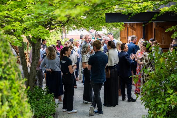 A group of people mingling outside at the Sherwood with trees surrounding the frame