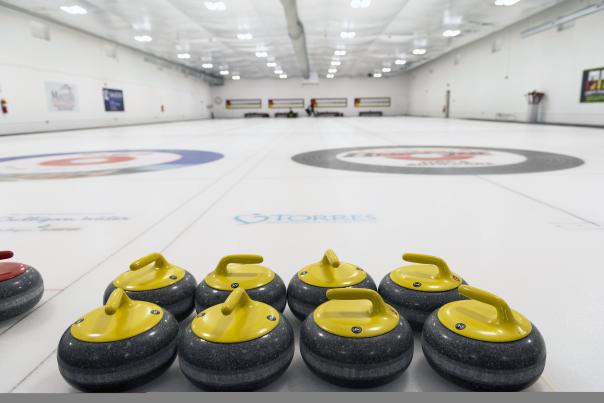 Eight yellow curling stones lined up on the ice at the Fort Wayne curling club.