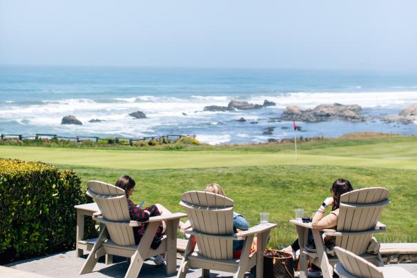Guests sitting on wooden chairs overlooking the Pacific Ocean at the Ritz-Carlton, Half Moon Bay in California