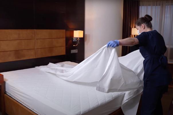Woman making a hotel room bed