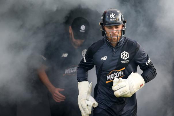 Cricket players walking onto pitch through smoke