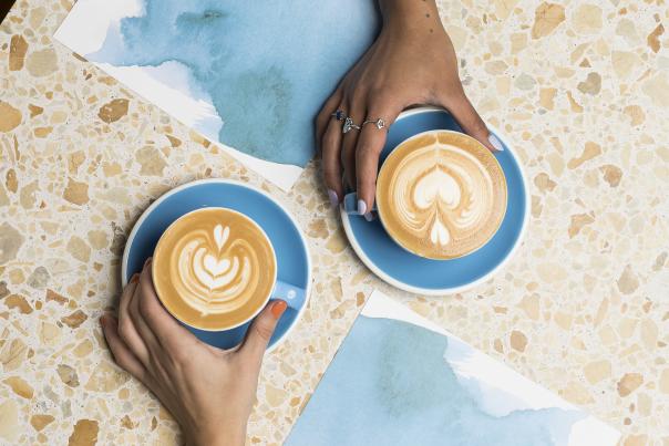 Two people holding coffee cups at Bluestone Lane Cafe in The Woodlands Texas