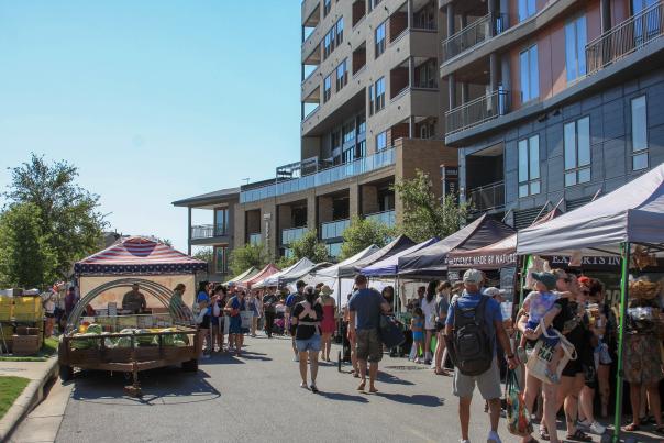 People walking between vendor tents at the Texas Farmers Market at Mueller.