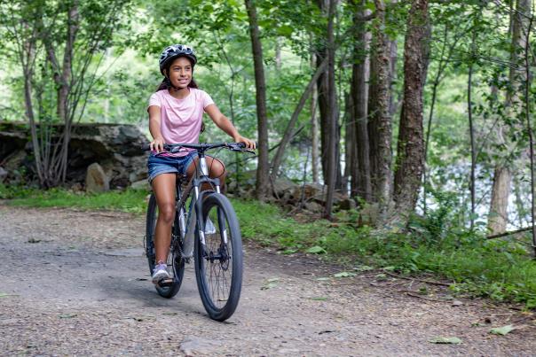 A girl bikes along a peaceful forest path in the Pocono Mountains.