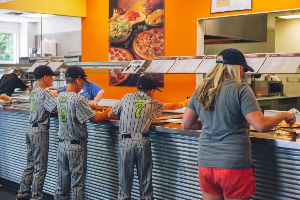 baseball players getting pizza at a pizza buffet