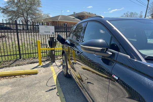 A black car plugged into an EV charging station.