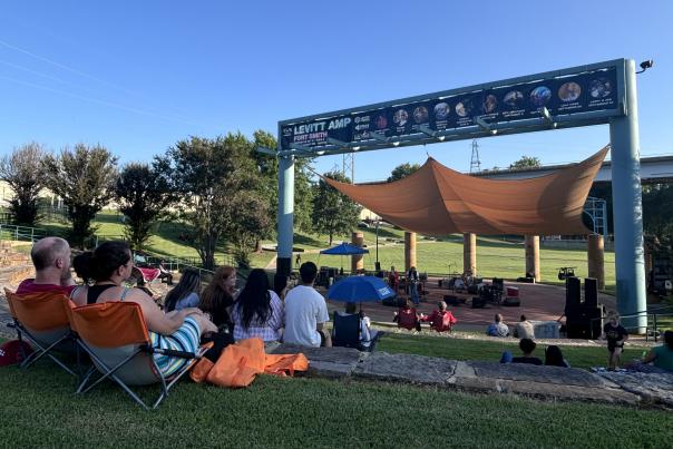 People sit in chairs on a green lawn to watch music at the Levitt Amp in Fort Smith, Arkansas.