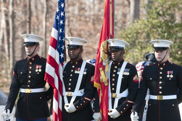 Marines in uniform holding flags for a ceremony