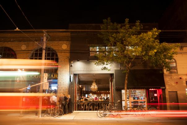 A streetcar passes an open restaurant bar at The Good Son and Dog & Bear on Queen Street West