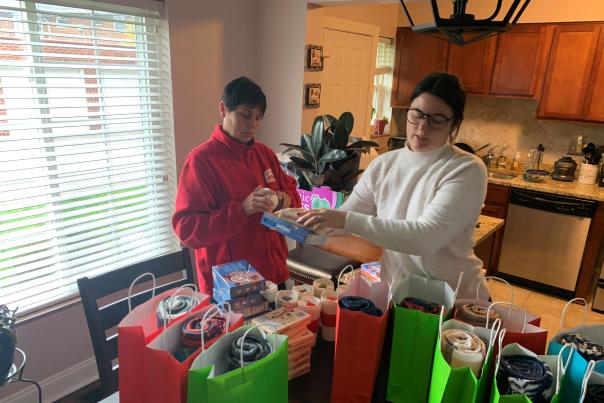 Two women pack holiday gift donations from home