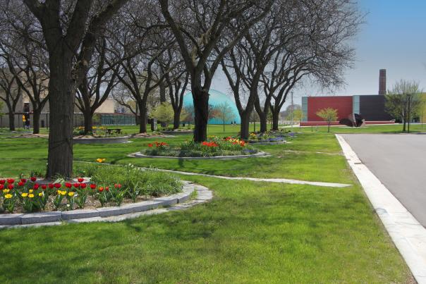 Spring flowers bloom around the trees in the grounds of the Flint Cultural Center with the Longway Planetarium dome and the Flint Institute of Arts in the background.