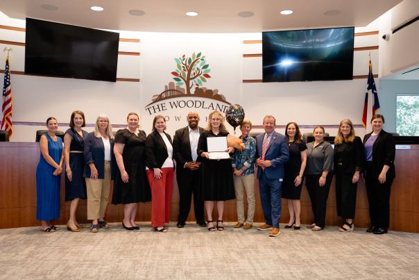Visit The Woodlands and The Woodlands Area Chamber pose in The Woodlands Township Board Chambers. Josie Lewis holds her Emerging Leader of the Year Award.
