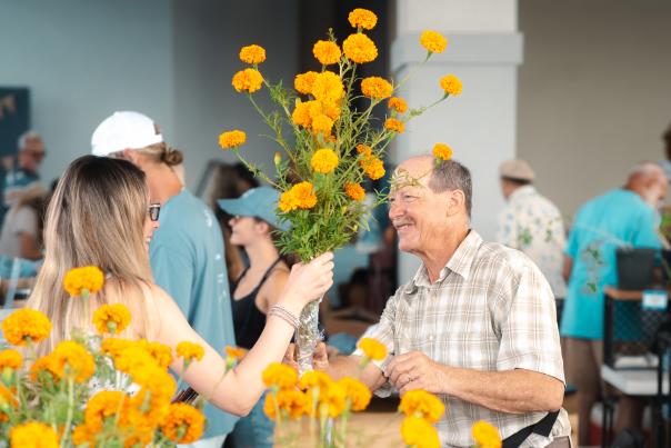 Woman handing a man yellow flowers.