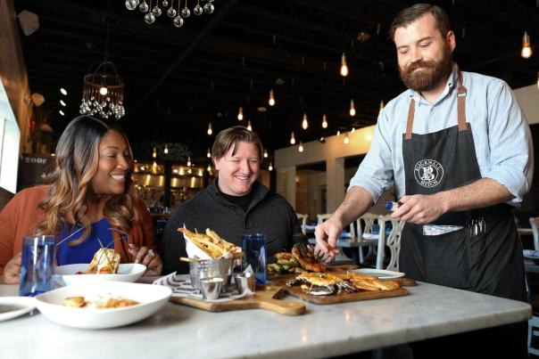 Annapolis restaurant Week image of couple sitting at a table with server placing food on the table