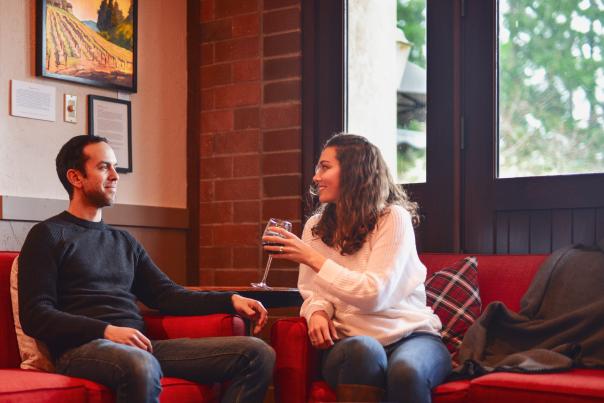 A couple sits on couches with wine in a tasting room