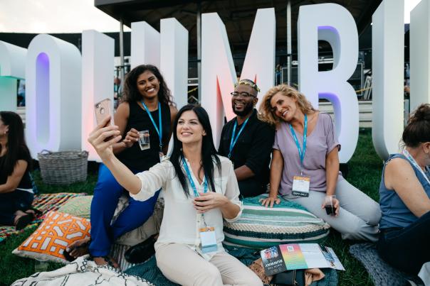Meeting attendees taking a group photo with Columbus sign at KEMBA Live! (formerly Express Live)