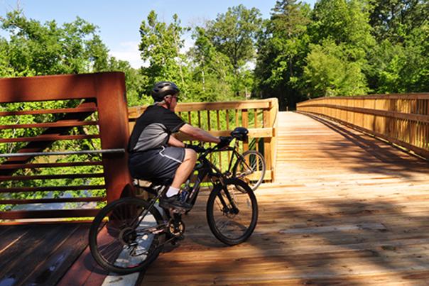 A man riding a bicycle on the Clayton River Walk in Clayton, NC.