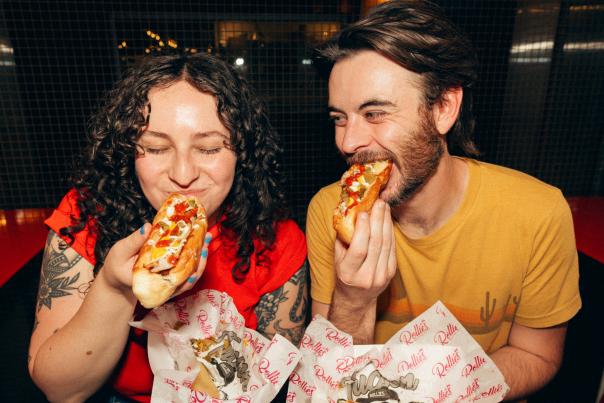 Two people enjoying sonoran hotdogs