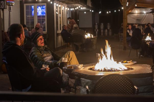 Two people enjoying a fire outside of Tap & Handle.