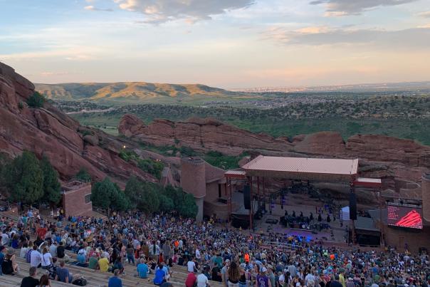 Red Rocks Amphitheatre crowds gathering before a show while it's still light out in the evening with Green Mountain and metro Denver in the background.