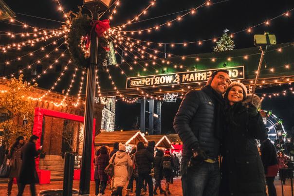 A couple walks through the Toronto Christmas Market in the Distillery District
