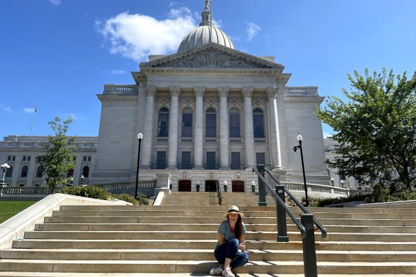 A woman sits in front of the Wisconsin State Capitol