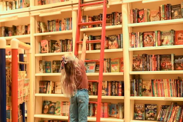 Girl climbing a ladder in Full Circle Bookstore