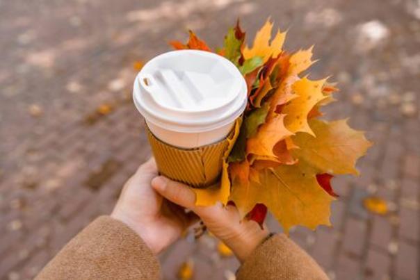 Hands holding coffee cup and fall leaves stock photo