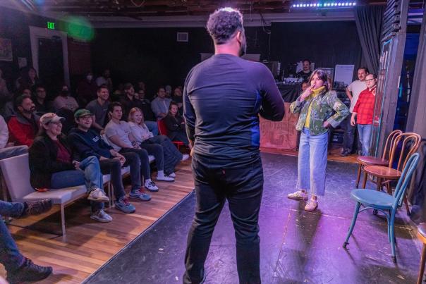 Two people on stage in the middle of an improv performance at ColdTowne Theater while the audience watches them.