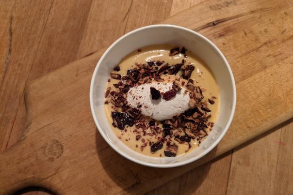 A bowl of butterscotch pudding from Bolete is topped with candied pecans and fresh whipped cream.