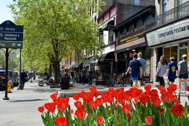 People walking along Broadway sidewalk with red tulips