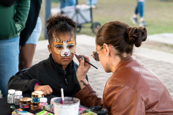 Young girl gettin her face painted by another woman. Fox designed face paint.