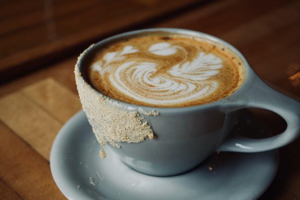 A latte in a blue coffee cup with beautiful latte art on top