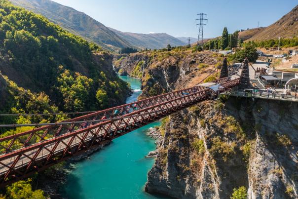 People biking over a bridge with vibrant blue water below